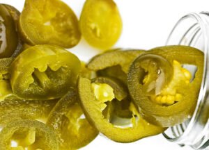 Sliced Jalapeno Peppers Coming Out Of Its Jar On White Background From Above